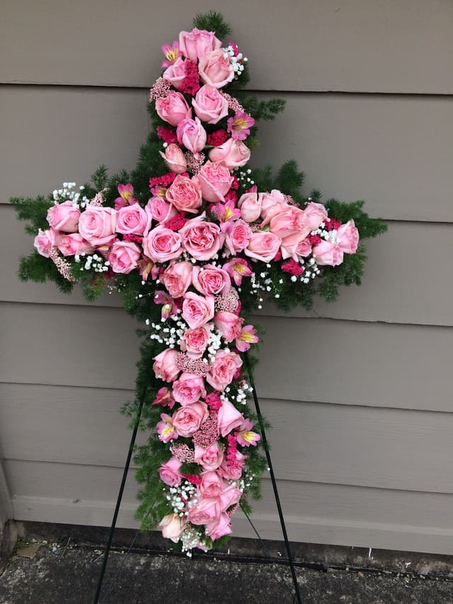 Sympathy standing cross covered in pink roses with baby’s breath