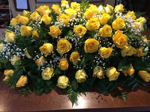 Casket spray of yellow roses with baby’s breath