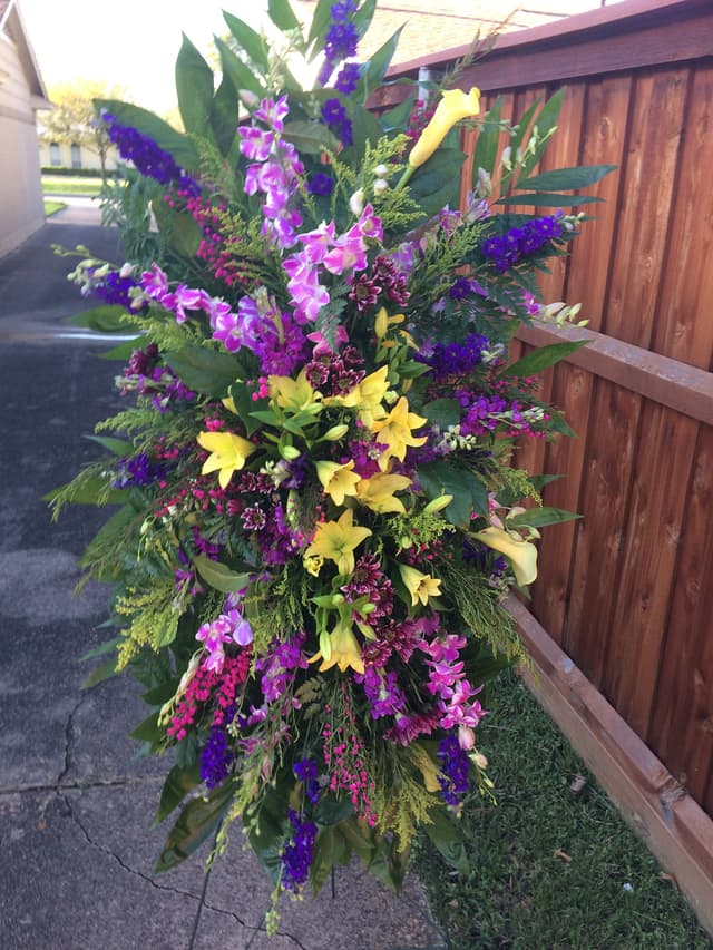 Sympathy standing spray with purple larkspur and yellow blooms