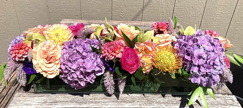 Long low tablescape of lavender, peach, and pink flowers