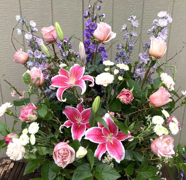 Sympathy fireside basket of pink lilies, roses, and purple delphinium