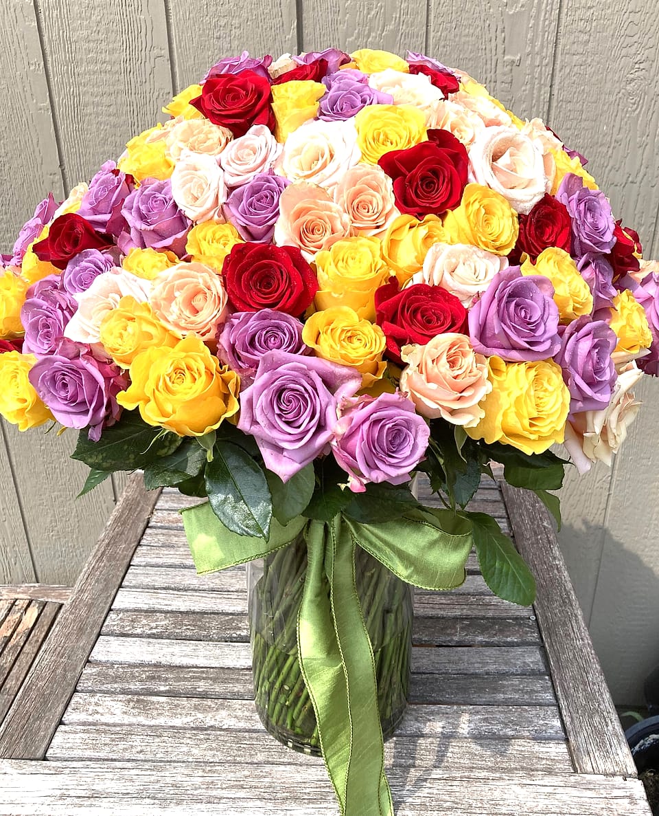 Hand-tied bouquet of 150 roses in lavender, yellow, red, and peach by Willow Creek Florist