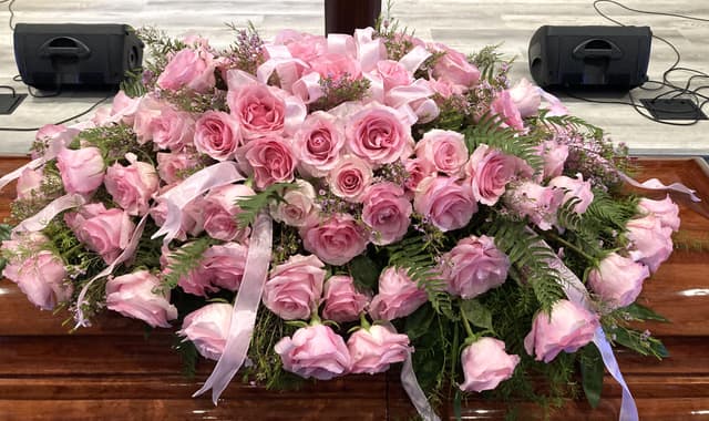 Casket blanket of soft pink roses with ribbon accents