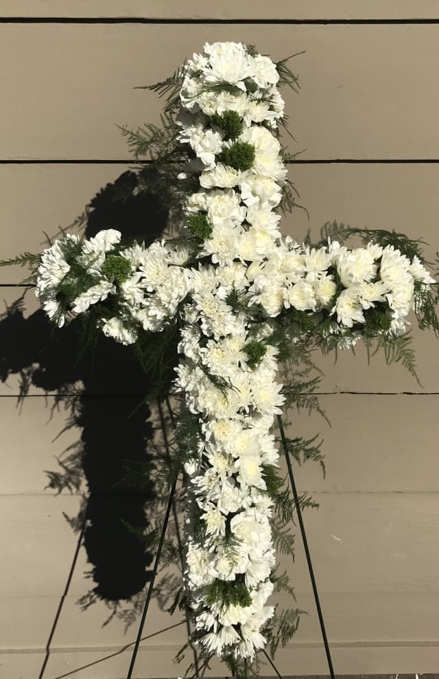 Sympathy standing cross of white flowers on a dark base