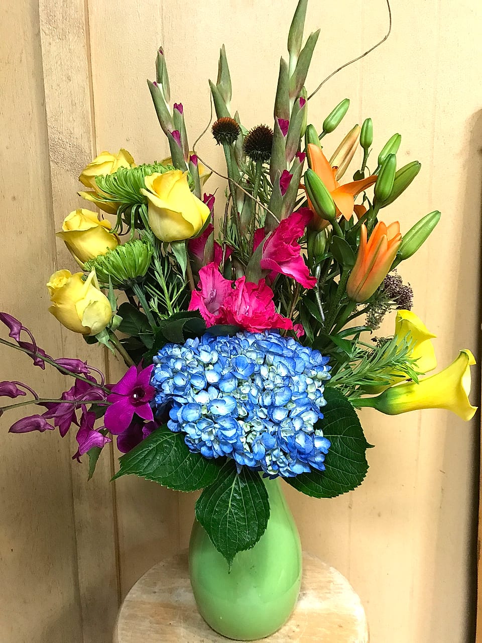 Vivid arrangement designed in blocks of color with roses, hydrangea, and calla lilies