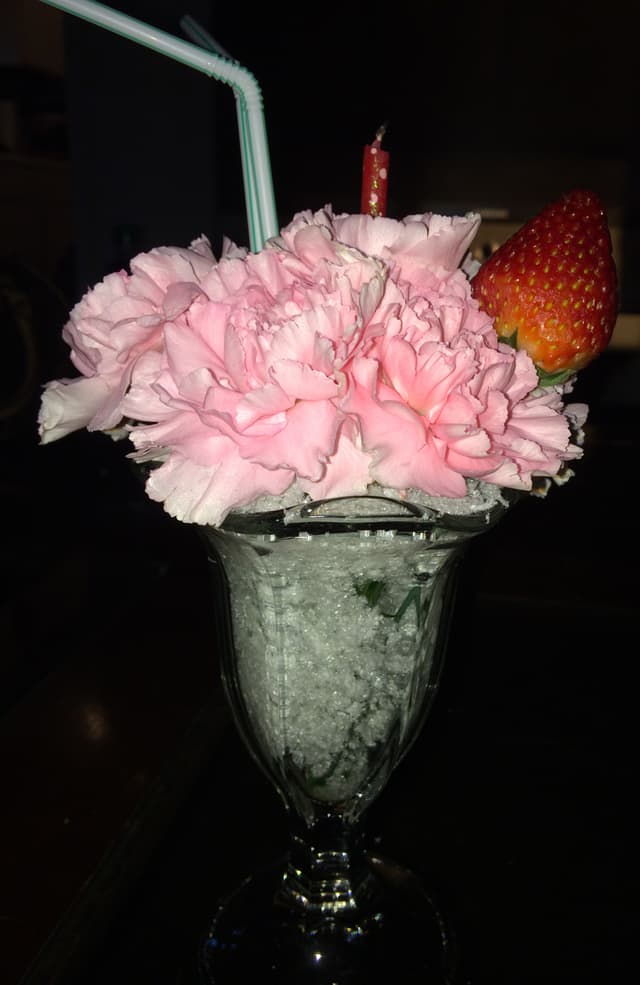 Pink carnations designed to overflow from a vintage soda glass