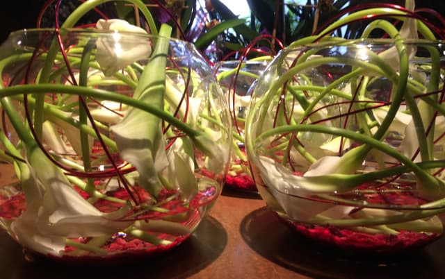 White calla lilies curled inside glass bubble bowls with warm lighting