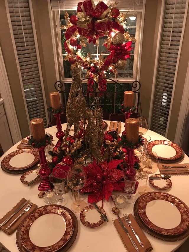 Holiday table with gold tree centerpiece, red accents, and coordinating wreath
