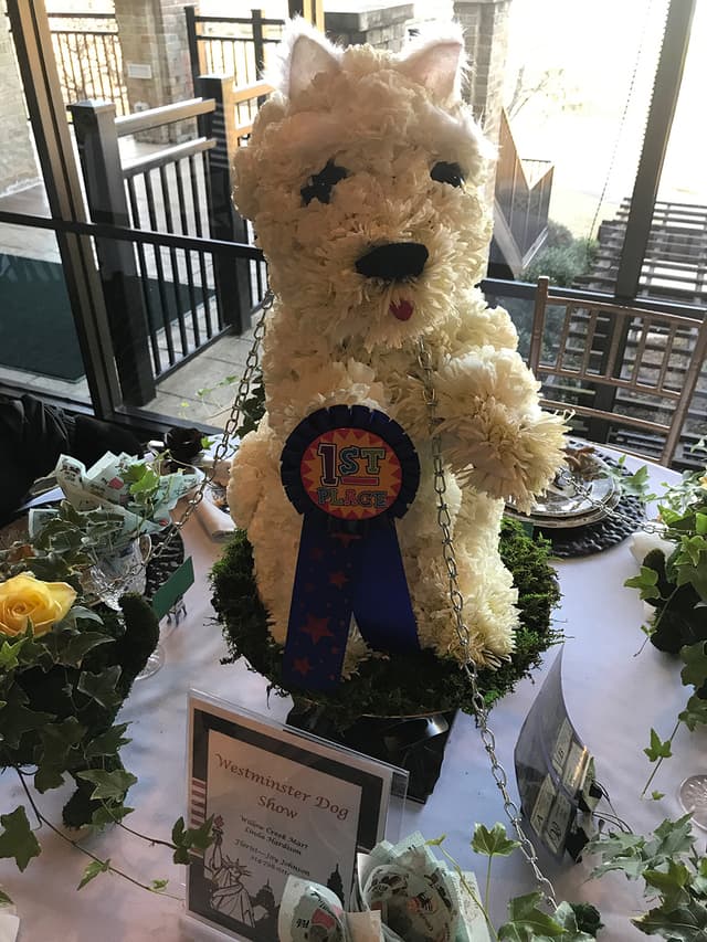 Prize-winning dog sculpture made of white carnations with a blue ribbon