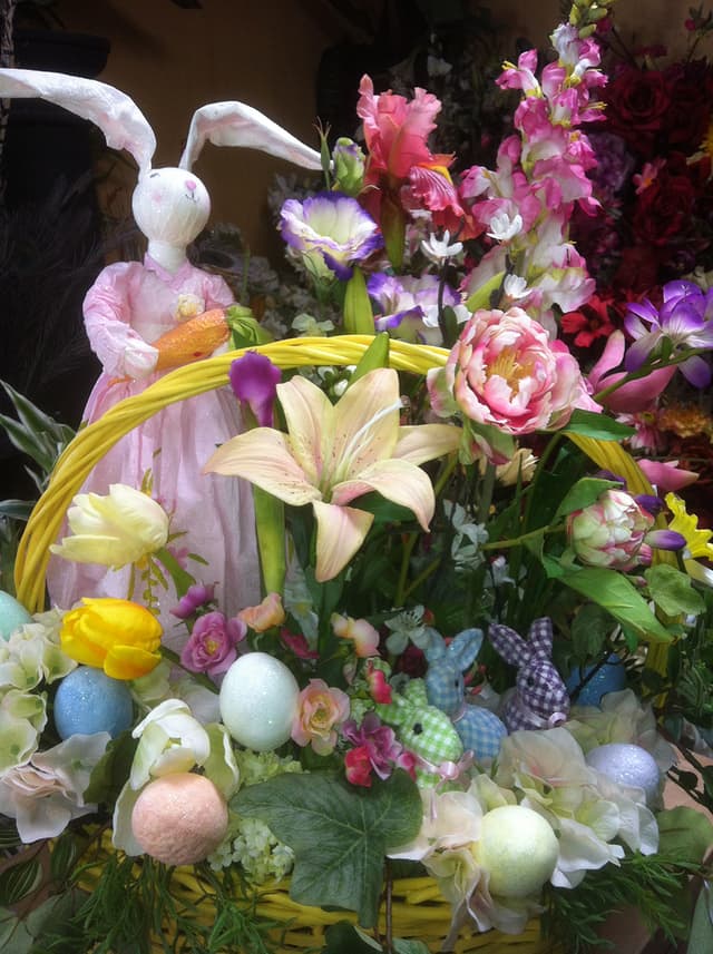 Easter basket scene with a plush bunny, spring lilies, and pastel flowers