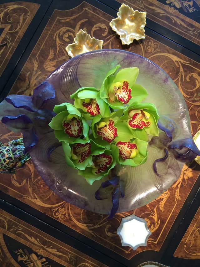 Green cymbidium orchids floating on a glass charger