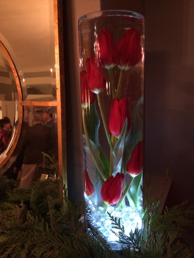 Red tulips submerged under water in a lighted glass cylinder