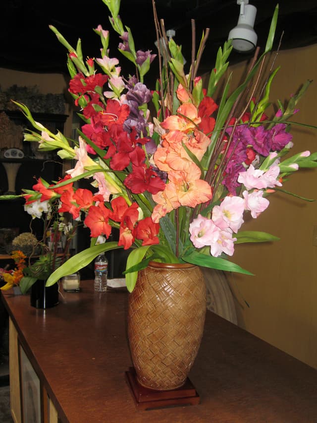 Silk gladiolas in coral and pink tones in a ceramic vase
