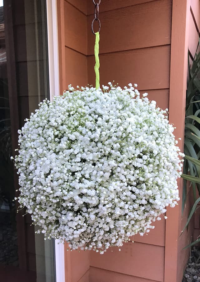 Oversized pomander sphere of baby’s breath hanging at an entry