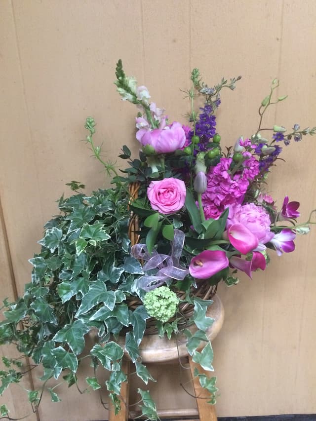 Arrangement of pink roses, tulips, and trailing ivy in a footed bowl