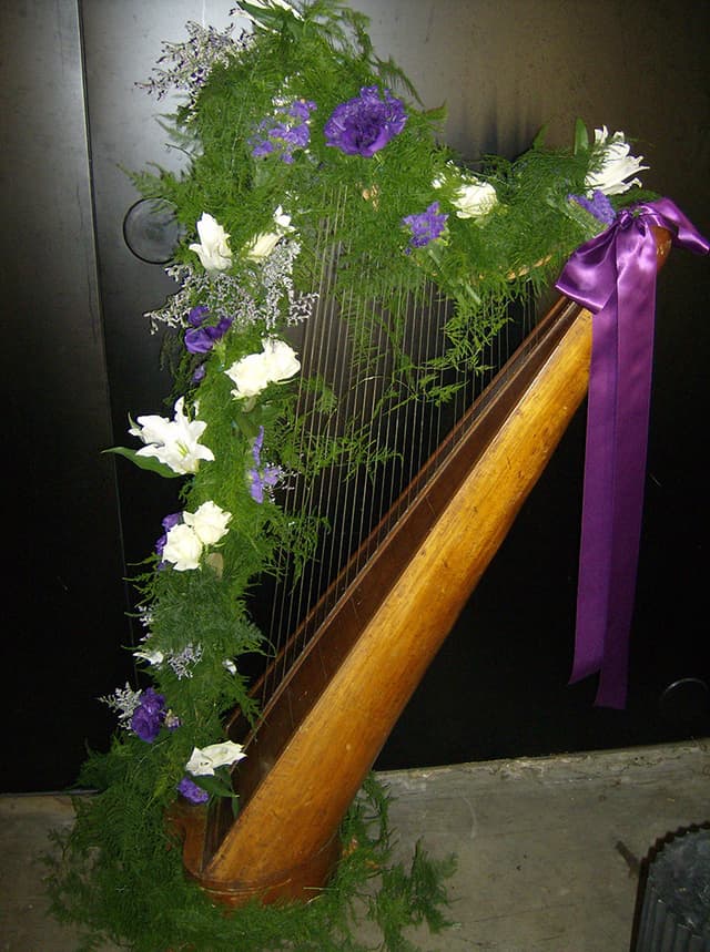 Harp decorated with ferns, white flowers, and a purple ribbon for a special occasion