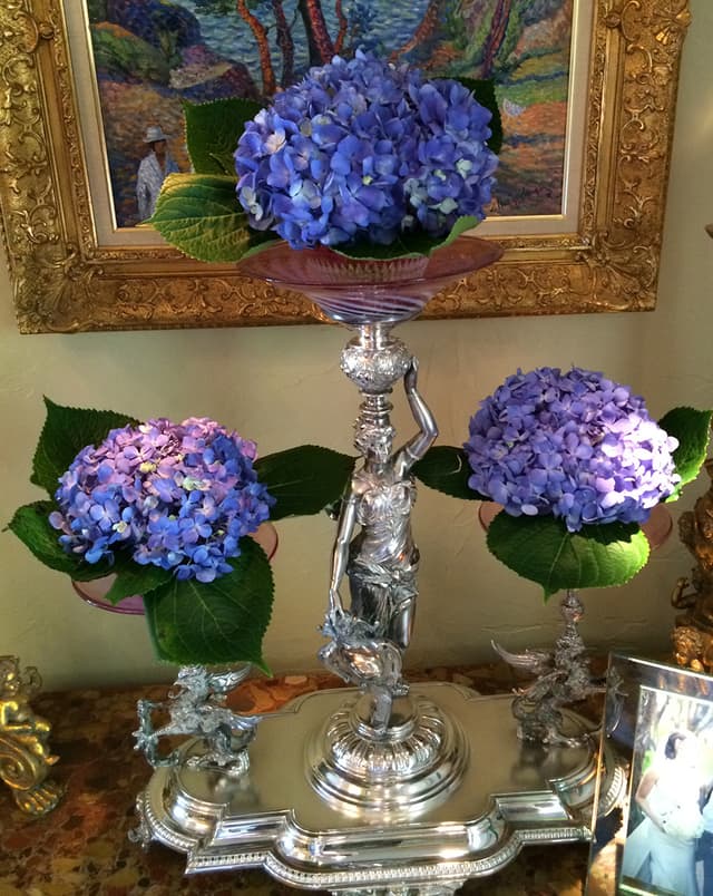 Silver epergne holding blue and purple hydrangea mounds