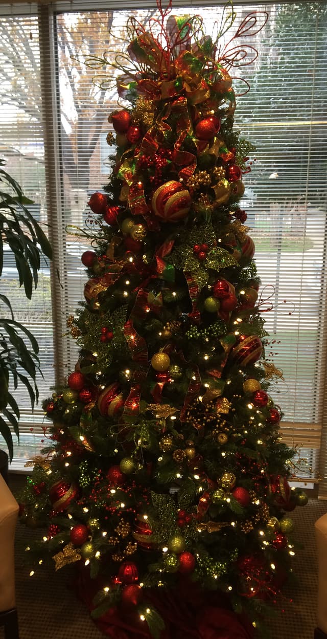 Tall red and green decorated Christmas tree in a building lobby