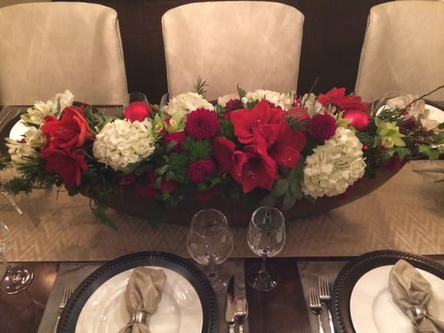 Long boat centerpiece of red roses, amaryllis, and white hydrangea