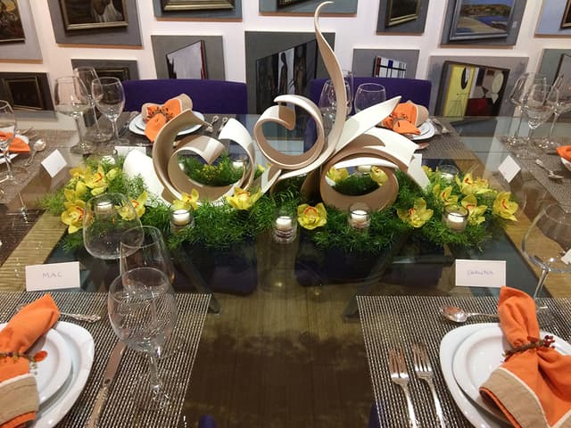 Modern sculptural tablescape with curled forms, moss, and candles