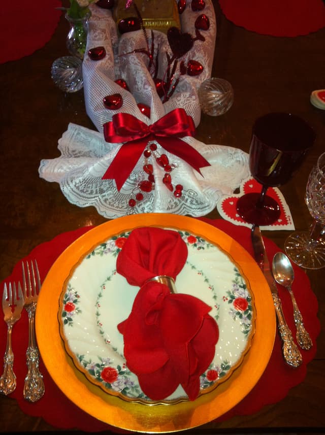 Valentine’s table setting with red napkins, lace hearts, and festive china