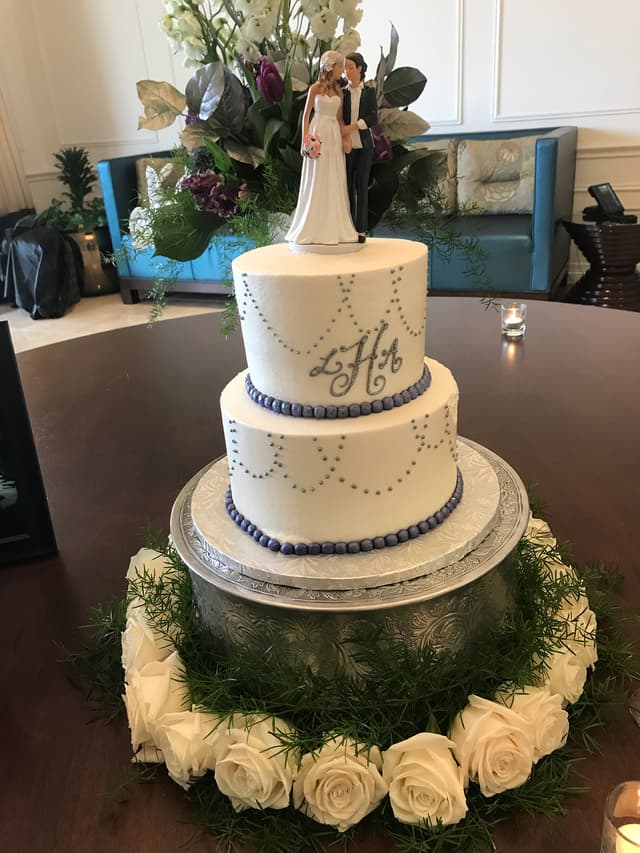 Three-tier white wedding cake with fresh floral trim on a moss base