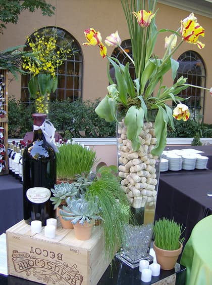 Wine tasting display with wheatgrass, garlic-strung trees, and succulents